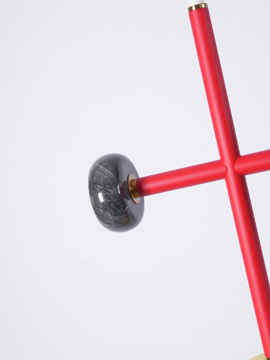 A second macro angle of the grey marble ball joint on a Clérachic chandelier's red cross-arm, showing the stone's natural veining up close.