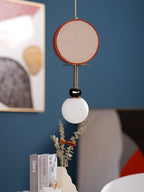 Clérachic pendant hanging beside a framed abstract print on a deep teal wall, with books and dried flowers below.