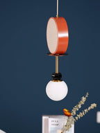 Clérachic pendant hanging against a dark navy wall, with dried eucalyptus and a book titled 'Full Stop' on the table below.