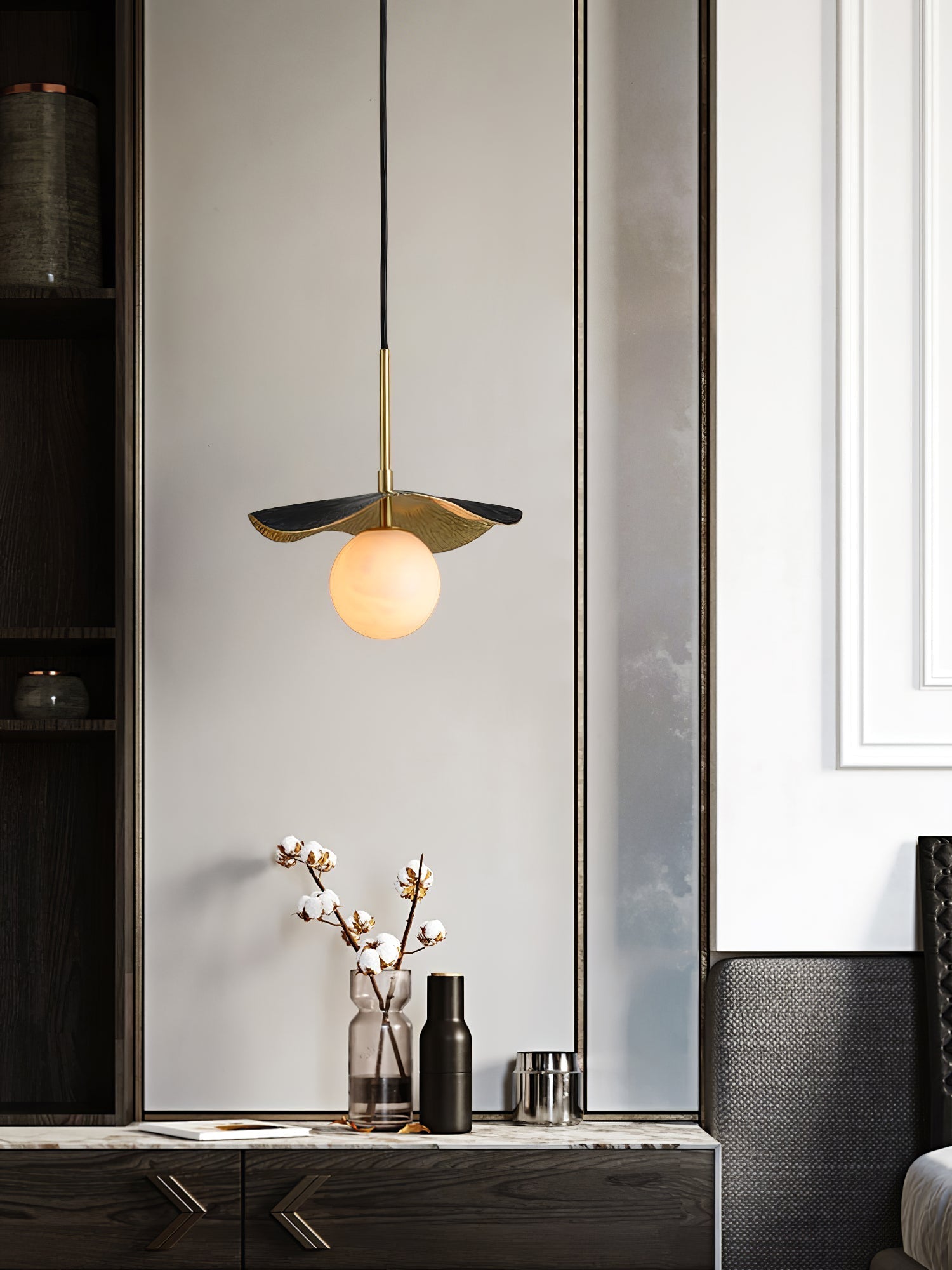 The pendant lit above a hallway console with cotton stems, framed by dark cabinetry