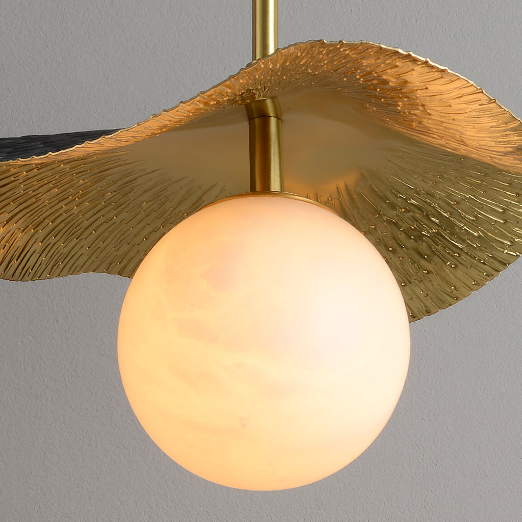 Close-up of the brass shade's hand-textured ridges curving above the glowing alabaster globe