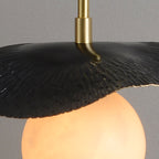 Detail of the black leaf shade's top surface where the slim brass stem meets the curved metal