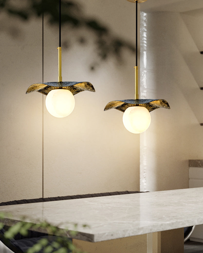 A pair of pendants lit above a marble kitchen island at night, globes glowing warm