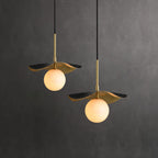 Two pendants against a charcoal studio wall, brass shades and alabaster globes shown at two heights