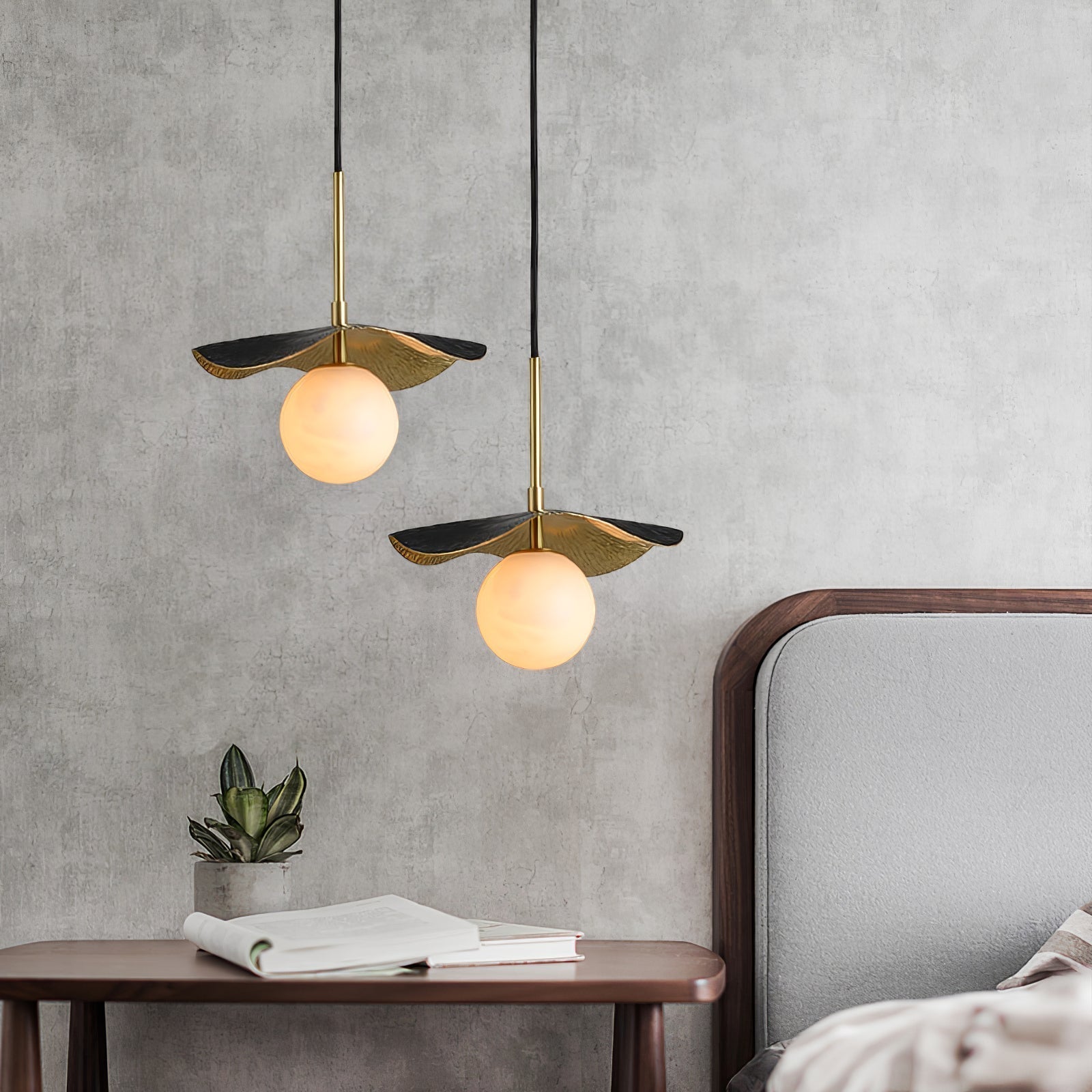 Square view of two staggered pendants lighting a concrete bedroom wall above a walnut side table