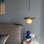 The pendant hung beside a bed against a blue-grey wall, its alabaster globe glowing over a nightstand