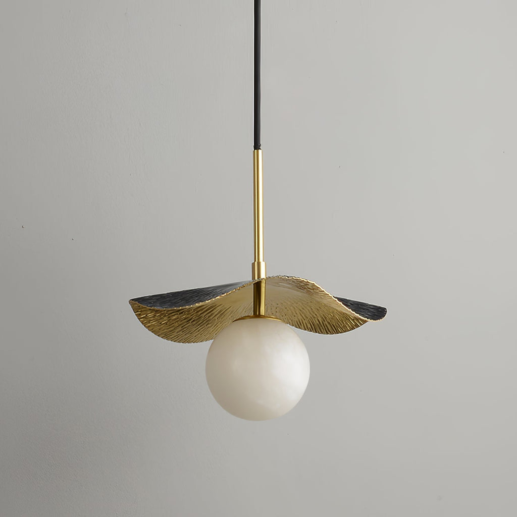 Zaraeen pendant against a pale grey wall, unlit, showing the brass shade's black-edged outer rim