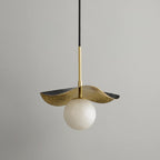 Zaraeen pendant against a pale grey wall, unlit, showing the brass shade's black-edged outer rim