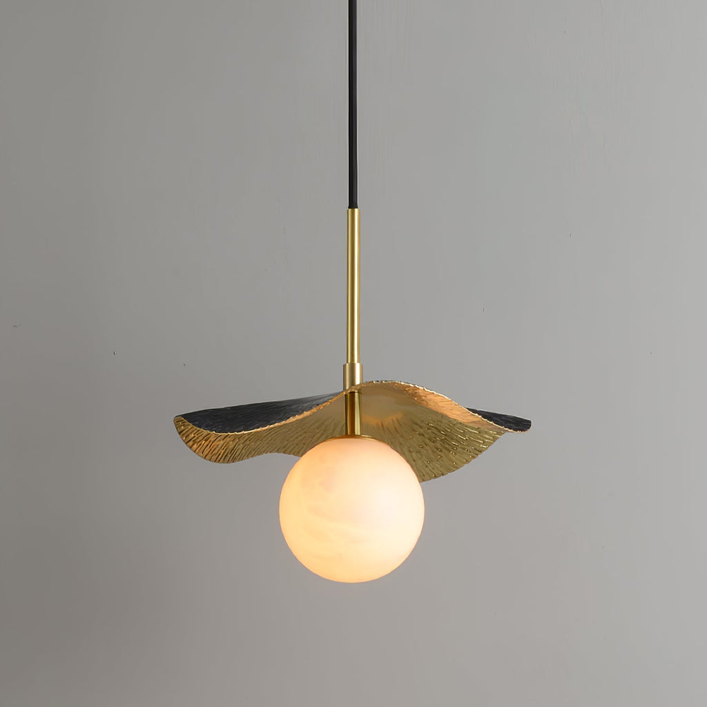 The brass pendant lit against a grey wall, warm light glowing through the veined alabaster globe