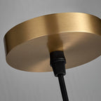 Close-up of the Hecate pendant's brushed brass ceiling canopy and the black cord grip beneath it.