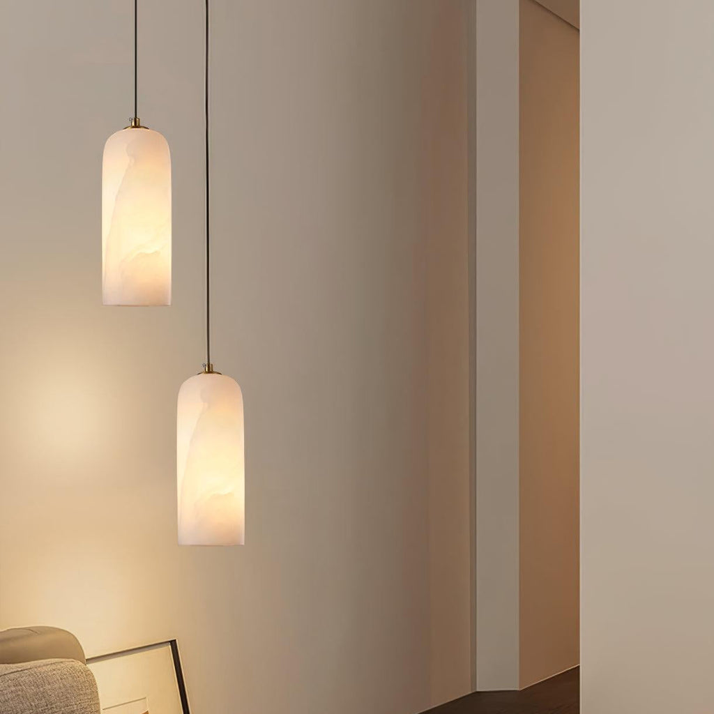 Two Hecate pendants hung at different drops in a pale corner, casting warm light down the wall.