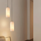 Two Hecate pendants hung at different drops in a pale corner, casting warm light down the wall.
