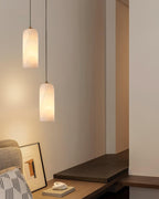 Two Zashayra pendants hung at staggered heights above a wooden desk, both lit warm.