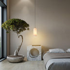 Hecate alabaster pendant on a long drop between a bonsai tree and a marble bedside cube.