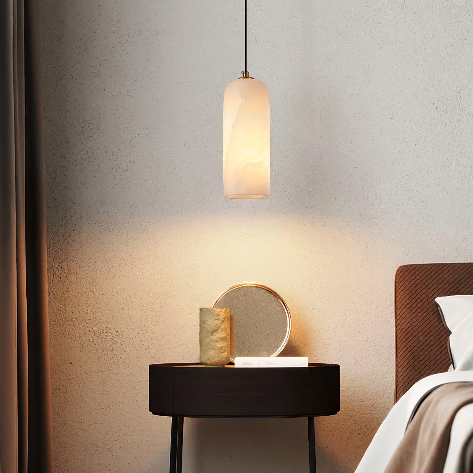 Hecate pendant lighting a dark bedside table against textured plaster, warm pool of light on the wall.
