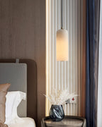Zashayra pendant beside a fluted wall panel and a bedside table holding a blue glass vase.