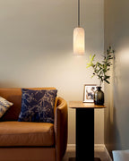 Zashayra pendant glowing beside a tan leather sofa and a slim side table holding an olive branch.