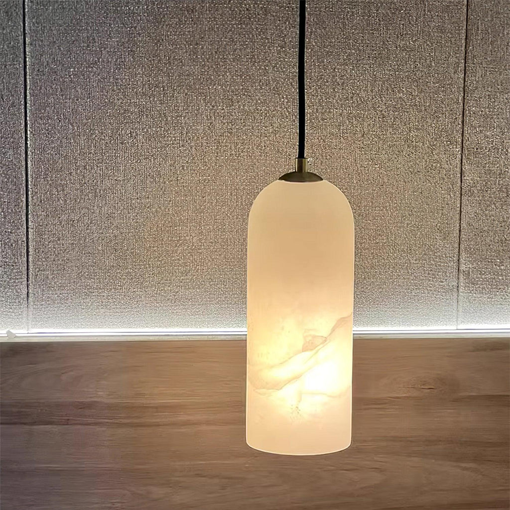 Hecate alabaster pendant glowing against a woven linen wall panel above a wood floor.