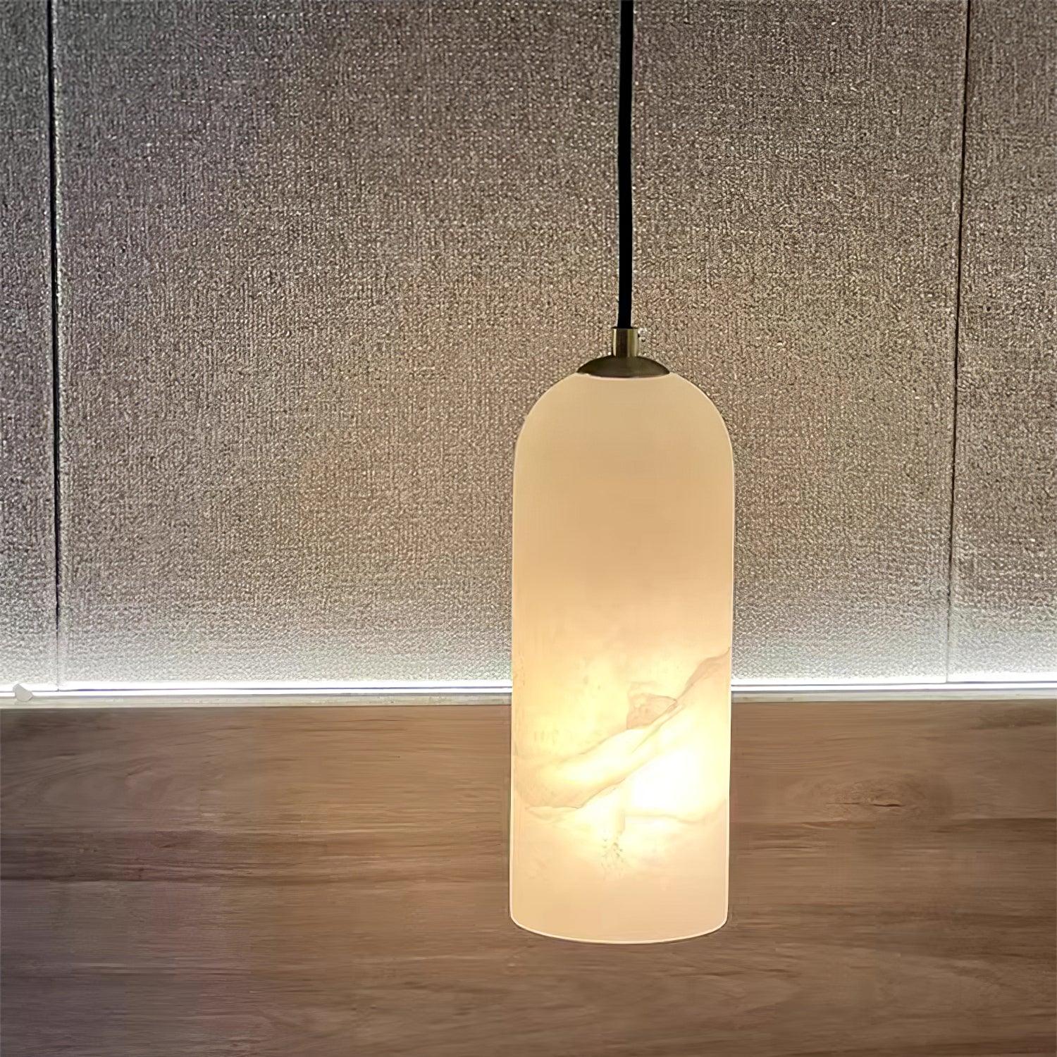 Hecate alabaster pendant glowing against a woven linen wall panel above a wood floor.