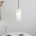 The Zashayra pendant over a round table set with a checkered mug and a slim metal sculpture.