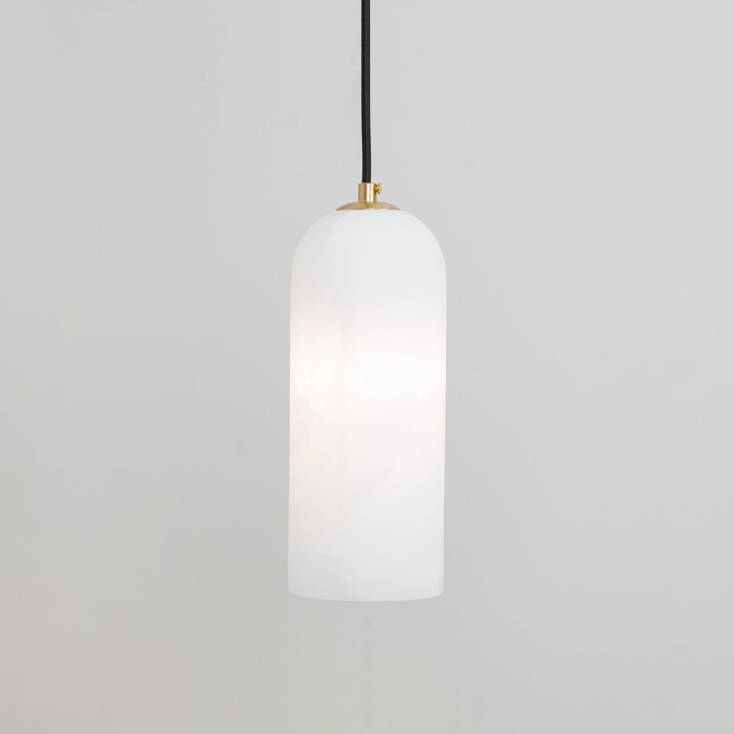 Zashayra pendant on a pale grey wall, lit softly so the light gathers in the middle of the shade.