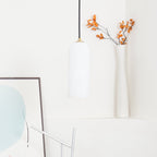 The unlit Zashayra pendant in a white styled corner beside a tall vase of dried orange branches.