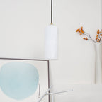 The unlit Zashayra pendant beside a framed blue abstract print, the alabaster reading cool white.