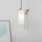 The lit Zashayra pendant with orange dried branches rising just behind its brass collar.
