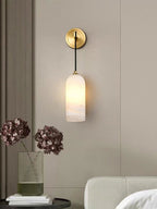 Wider view of the Vaelara sconce on a greige wall, above a round side table with stacked books