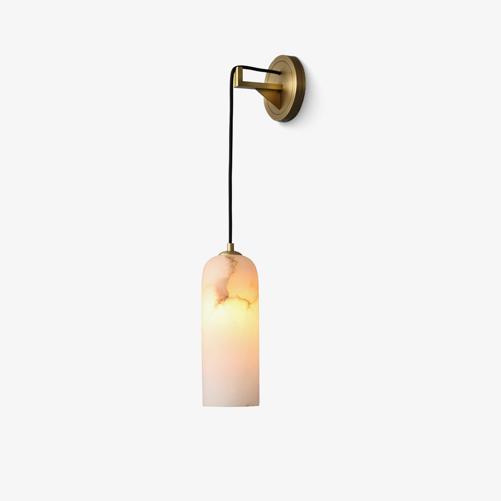 Vaelara alabaster wall sconce mounted with the brass backplate to the right, shade lit, on a white background