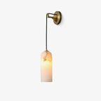 Vaelara alabaster wall sconce mounted with the brass backplate to the right, shade lit, on a white background