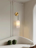 Vaelara sconce lit on ornate cream wall panelling above a curved sofa with green knot cushions