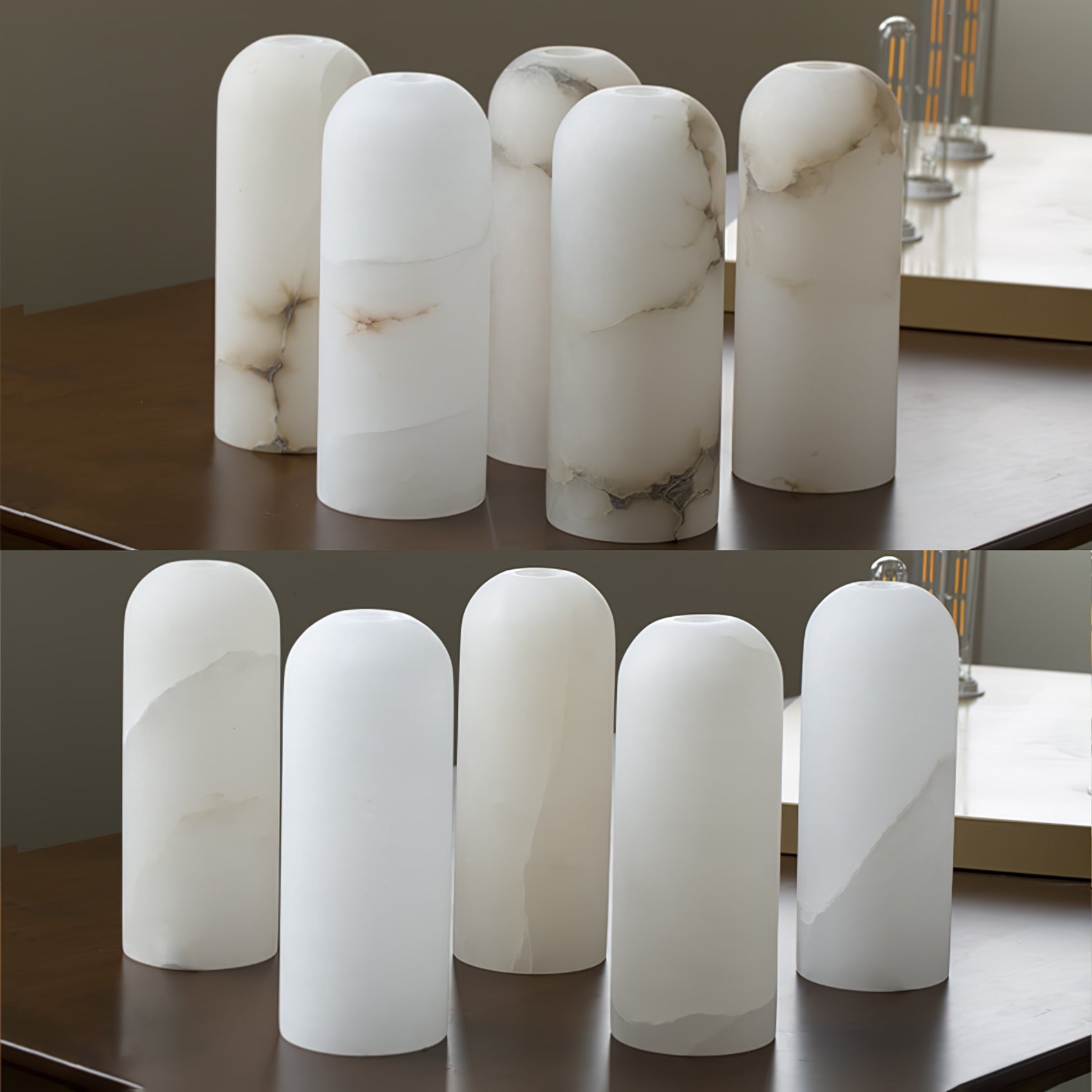 Ten unlit alabaster shades lined up on a dark table, showing how the natural veining varies