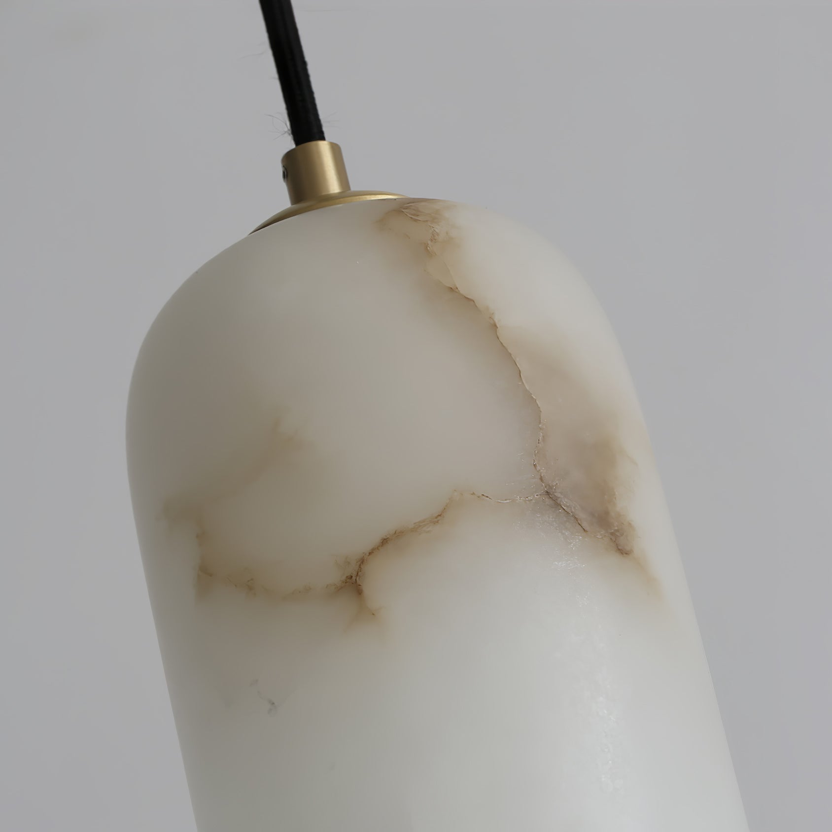 Close-up of the alabaster shade's brass collar and fabric cord, with the stone's brown veining