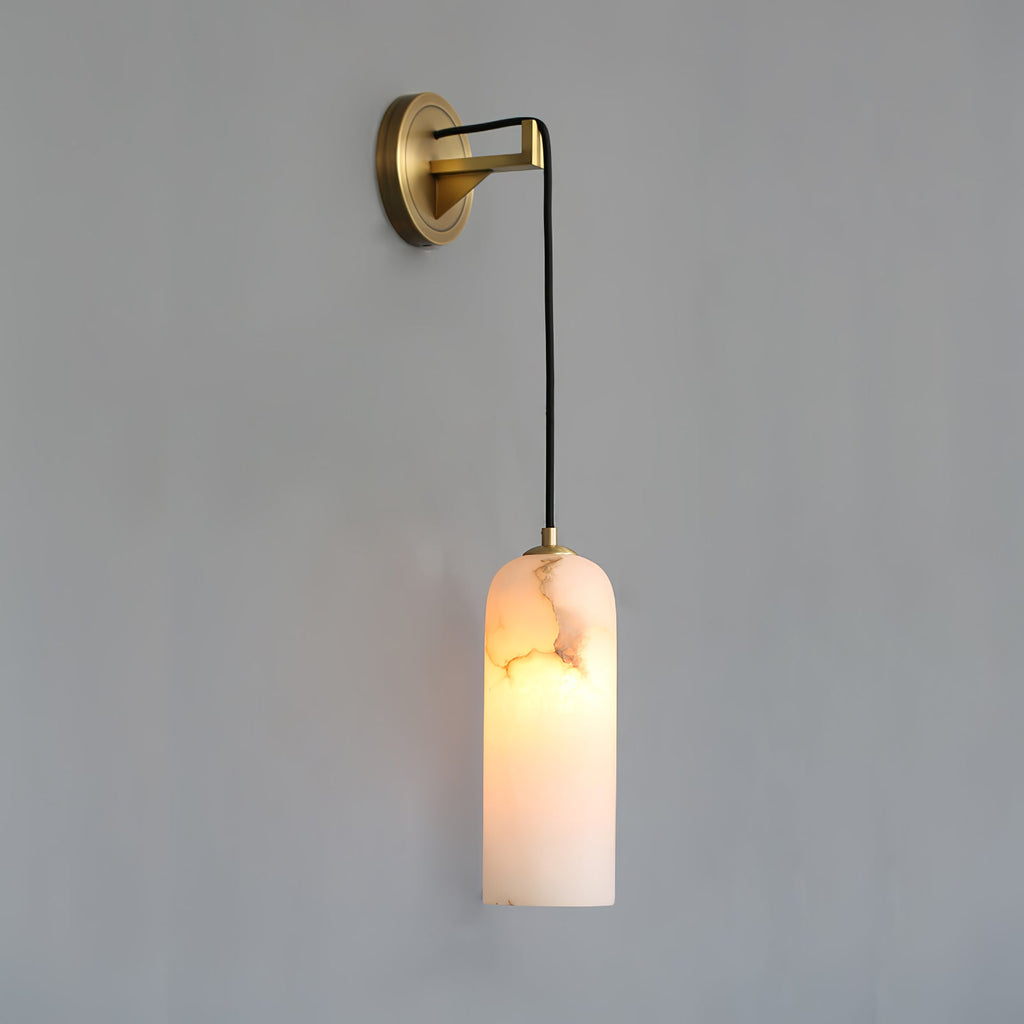 Vaelara alabaster wall sconce with a long cord drop, lit shade hanging well below the brass arm