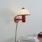 Mushroom wall lamp lit above a bedside table at night
