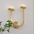 Brass Vitalira Double Alabaster Wall Light lit head-on, its two arms sweeping into a wide U.