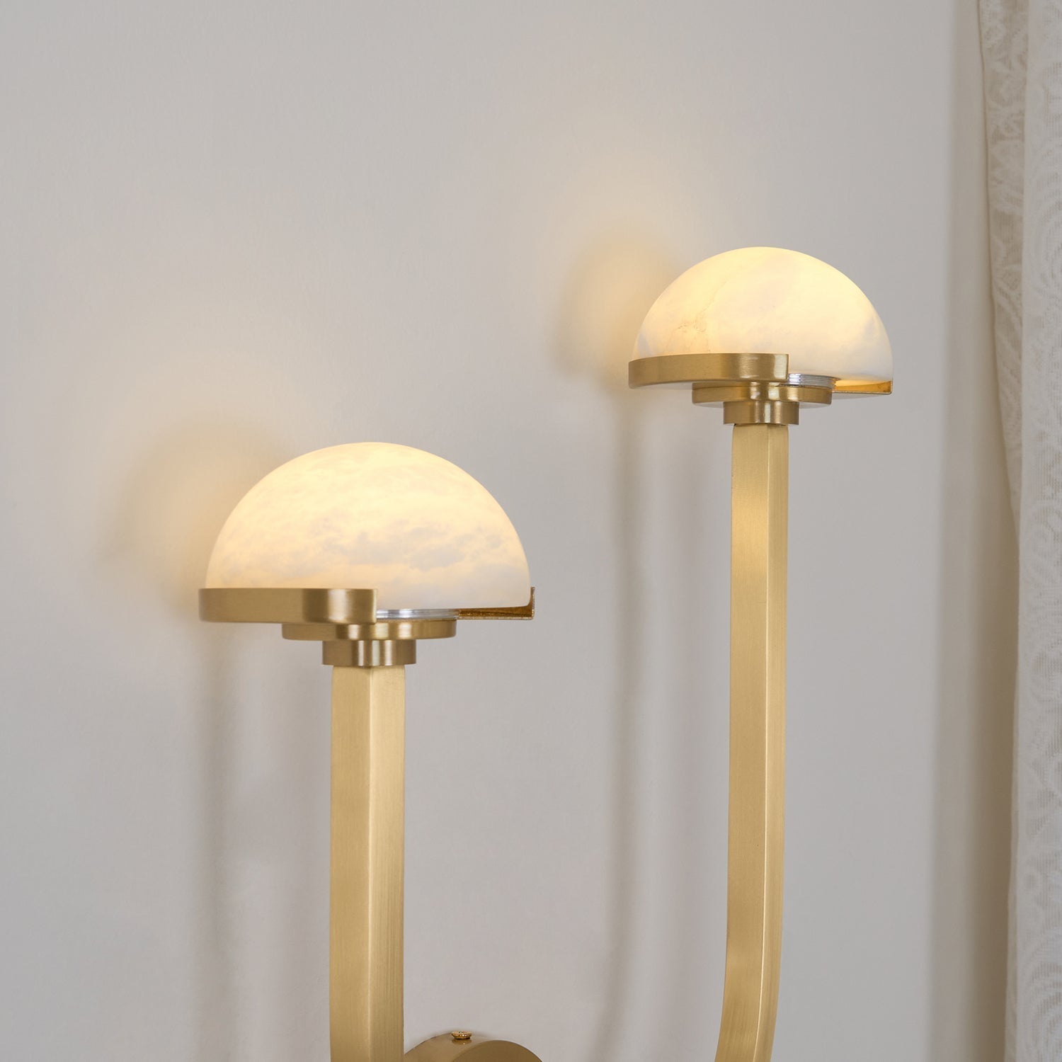 Both alabaster domes of the brass Vitalira wall light lit, throwing soft pools of light on the wall.
