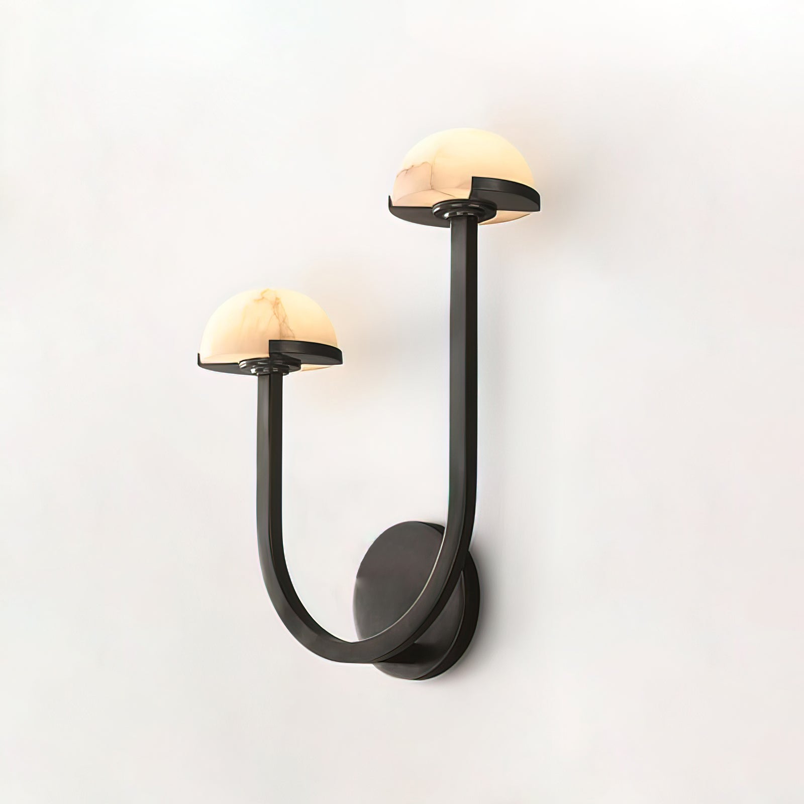 Vitalira Double Alabaster Wall Light in black lit on a white background, both domes glowing softly.