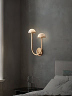 Brass Vitalira Double Alabaster Wall Light lit in a grey bedroom corner beside a nightstand and glass.