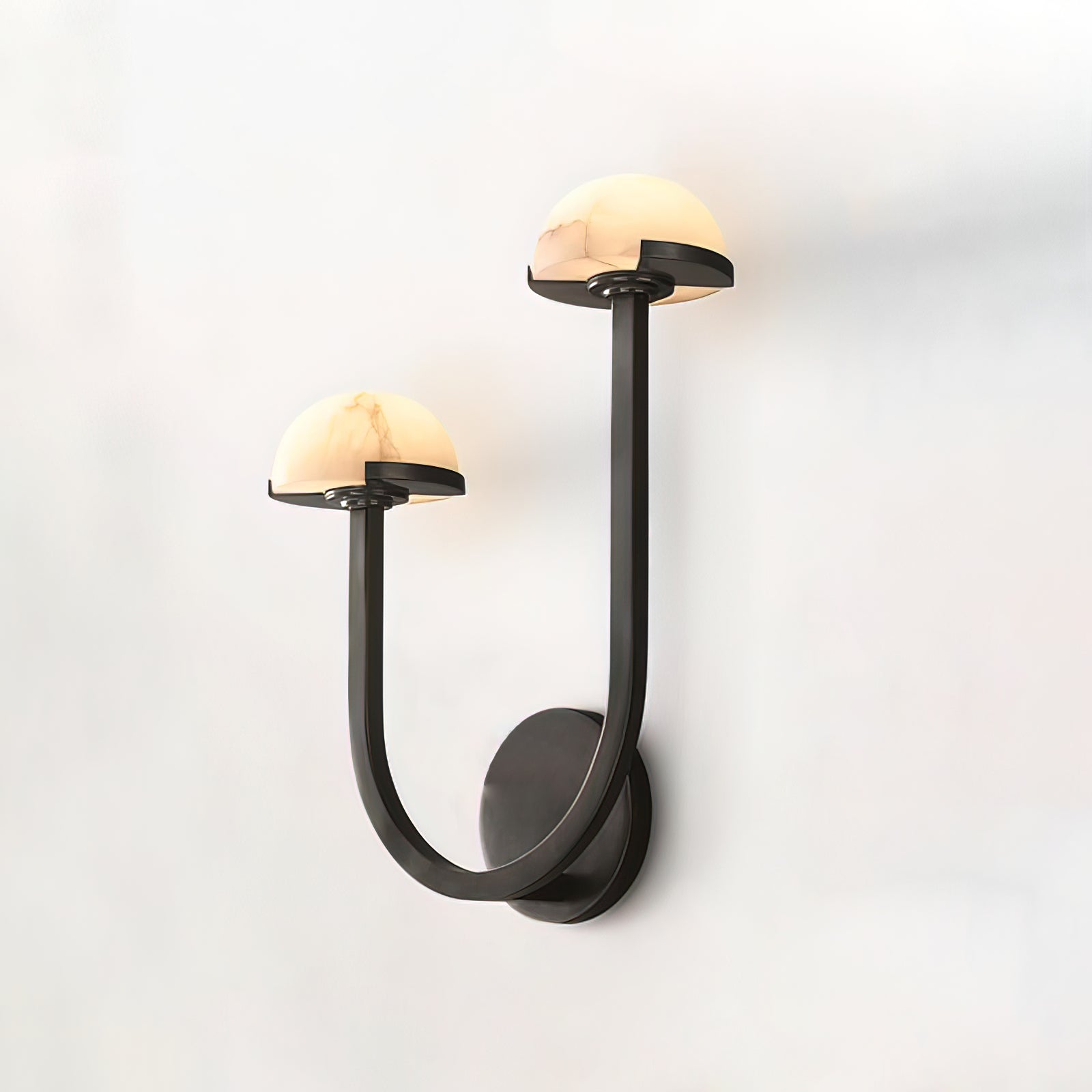 Vitalira Double Alabaster Wall Light in black photographed against a white wall from a raised angle.