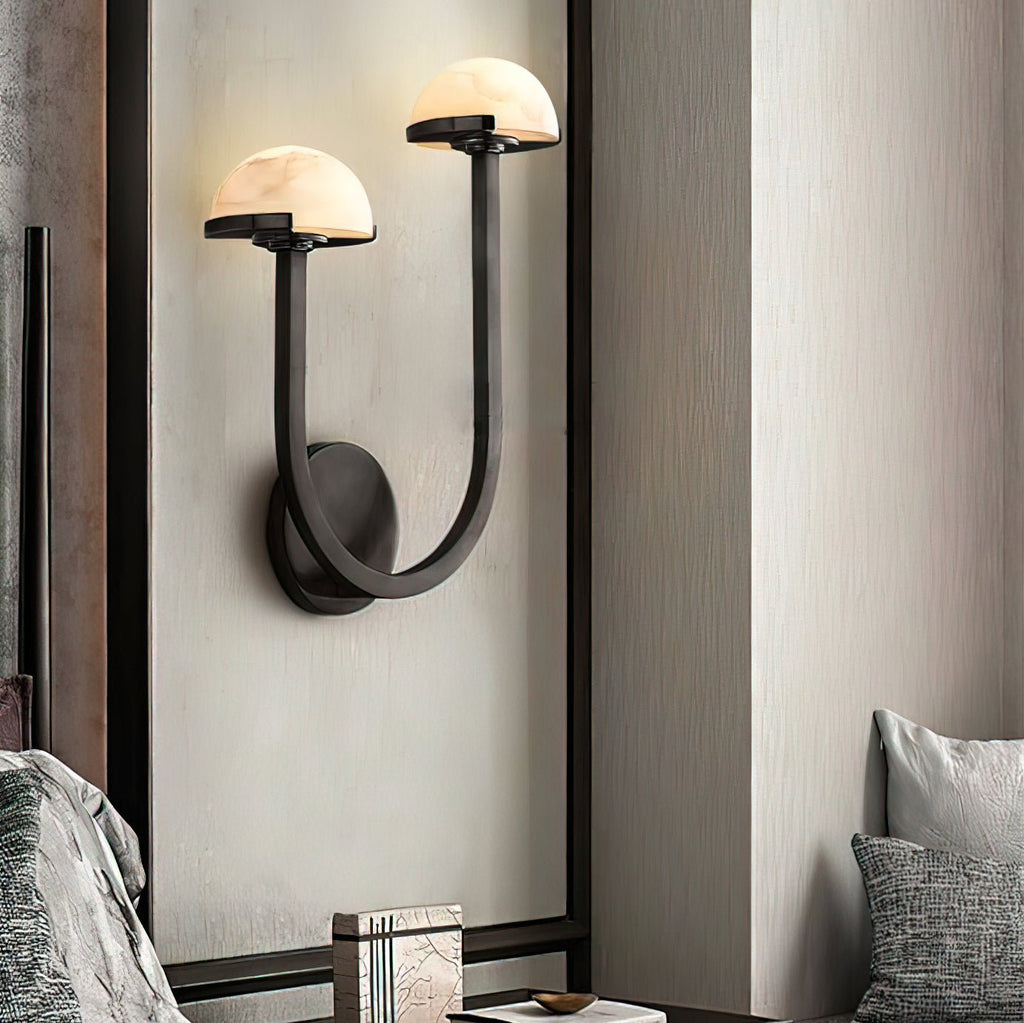 Vitalira Double Alabaster Wall Light in black lit on a panelled bedroom wall above a stack of books.