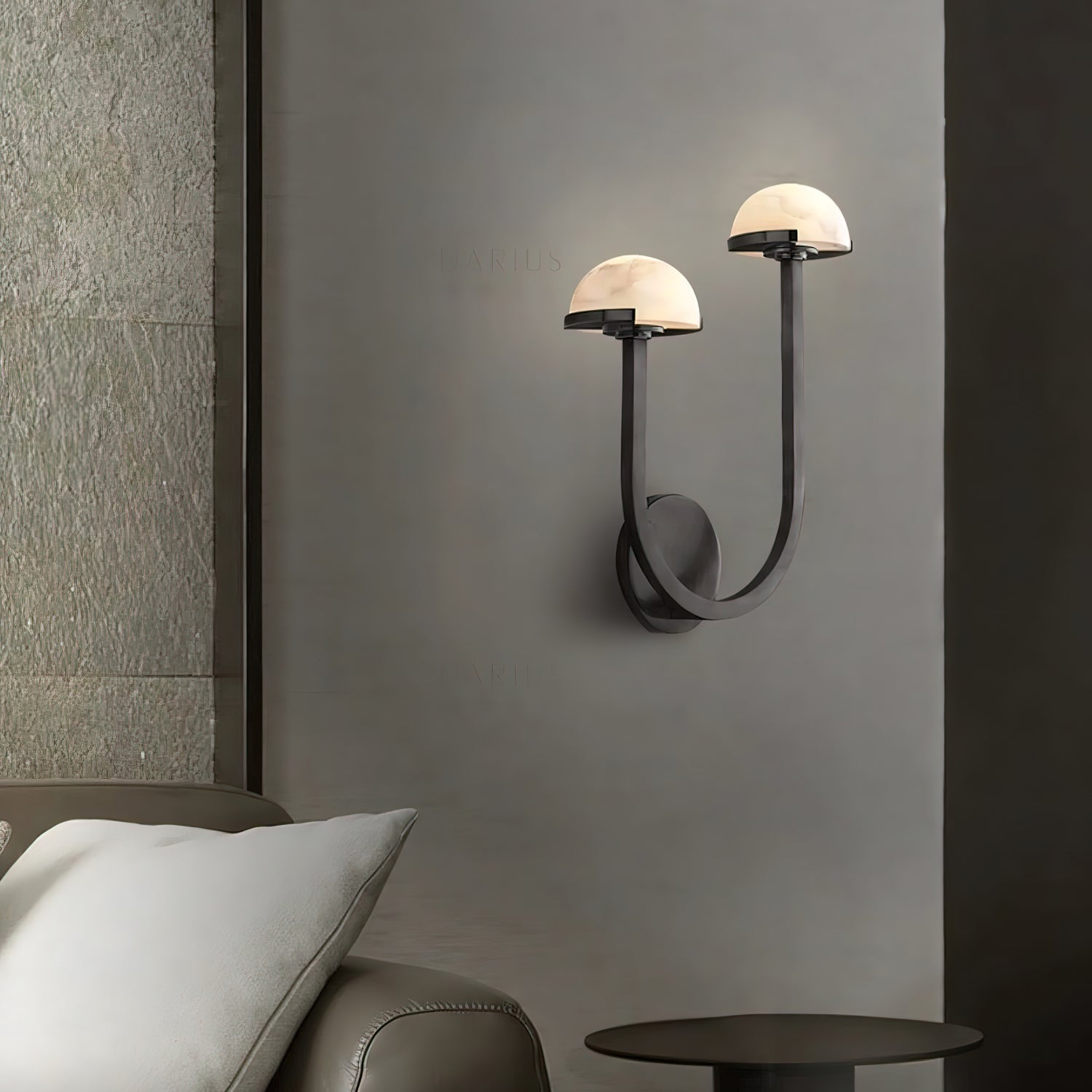 Vitalira Double Alabaster Wall Light in black lit beside a bed, casting a warm halo on the grey wall.