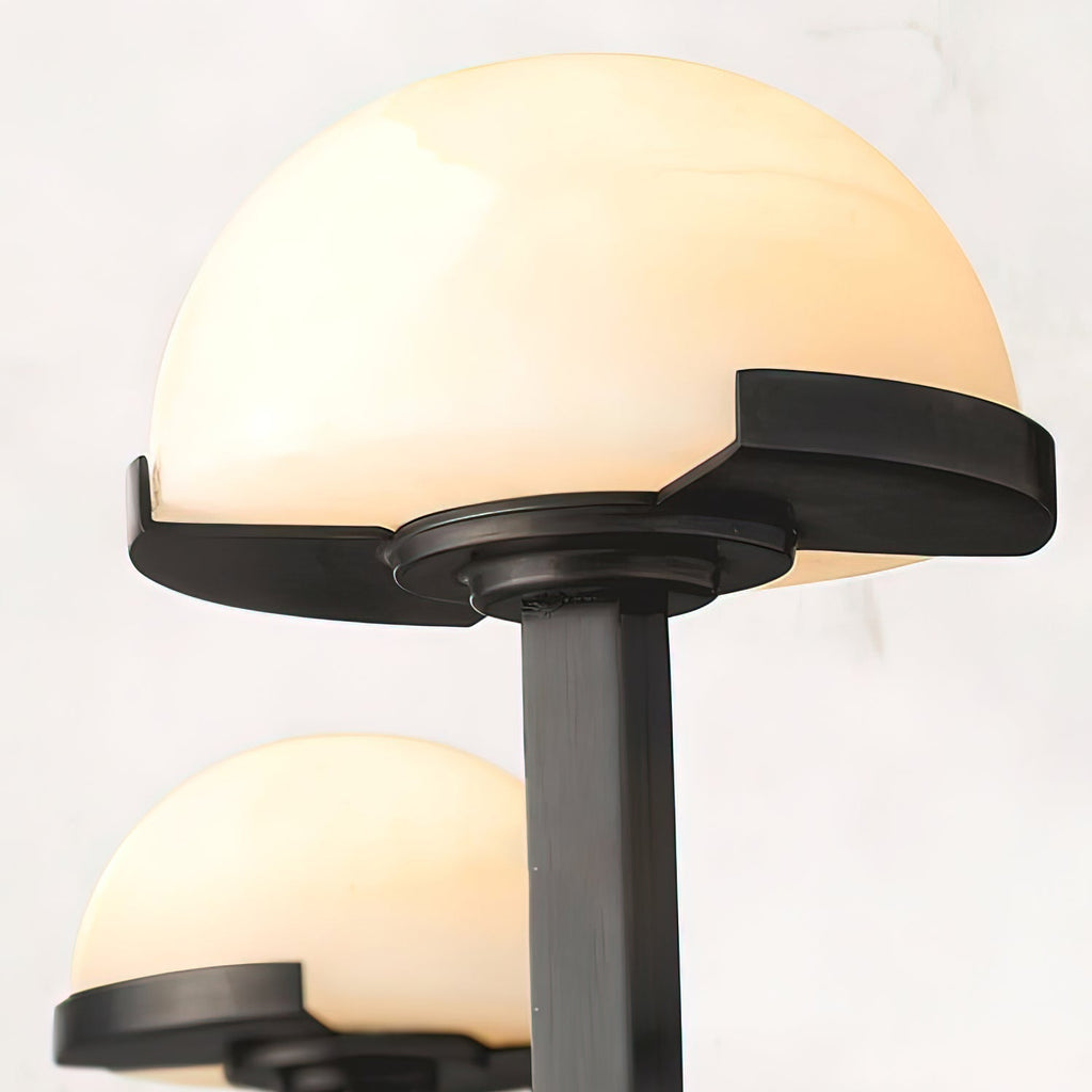 Close-up of one lit alabaster dome on the black Vitalira wall light, showing the stepped dark trim.