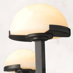 Close-up of one lit alabaster dome on the black Vitalira wall light, showing the stepped dark trim.