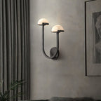 Black Vitalira Double Alabaster Wall Light lit in a living room, curtains left and framed art right.