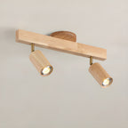 Natural wood track spotlight heads angled over a wall