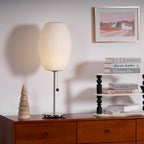 Faux silk bubble table lamp with chrome stem lit warmly on a side table