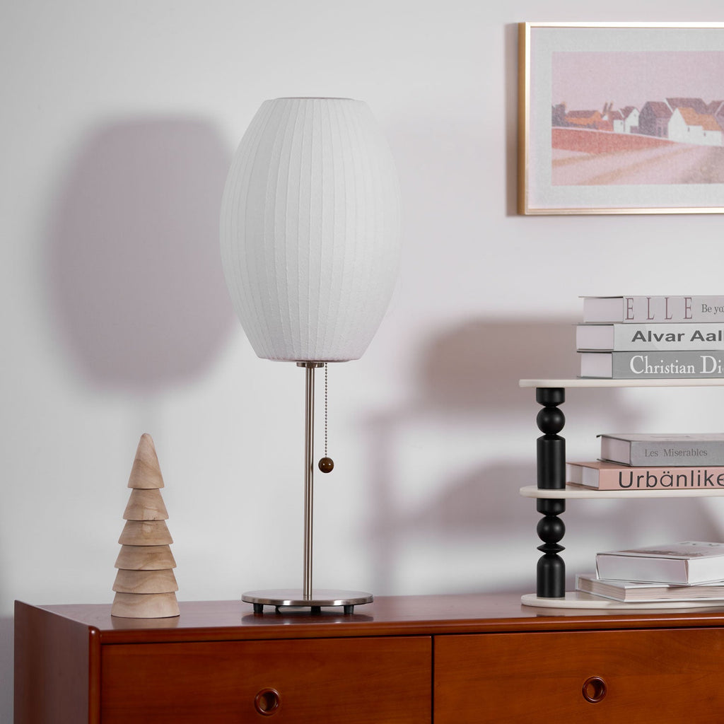 Faux silk bubble table lamp with chrome stem lit warmly on a side table