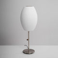 Faux silk bubble table lamp with chrome stem lit warmly on a side table